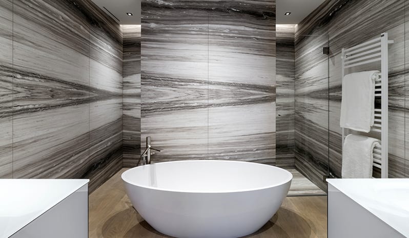 Lago Penthouse Suite Contemporary white oval soaking tub with floor-mounted faucet in a modern marble bathroom setting at ARIA Retreat & SPA by Kenwood Travel