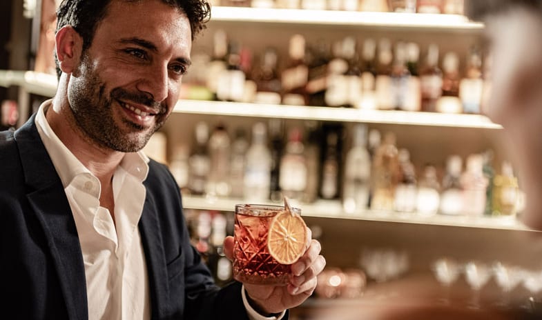 Dolce Vita Lounge & Terrace Man holding a craft cocktail garnished with a dehydrated orange slice at ARIA Retreat & SPA by Kenwood Travel