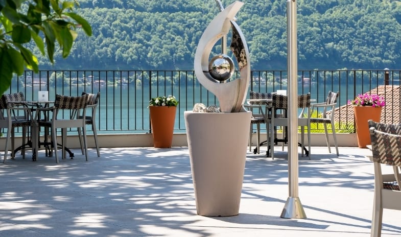Sky Lounge Lakeside hotel terrace with outdoor seating, a modern centerpiece sculpture, and scenic mountain views at ARIA Retreat & SPA by Kenwood Travel