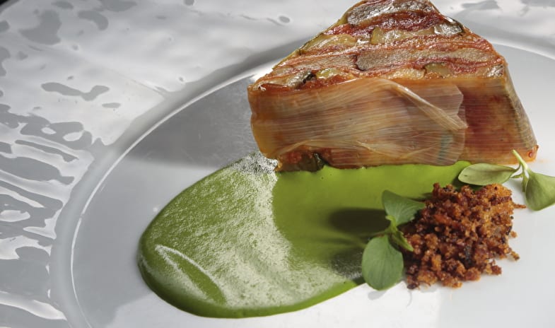 La Musa Restaurant & Rooftop Terrace Gourmet layered vegetable terrine with vibrant green herb puree and crispy crumble on a white textured plate at ARIA Retreat & SPA by Kenwood Travel