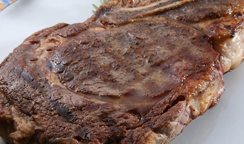 La Masseria Restaurant Juicy grilled bone-in ribeye steak with a golden-brown crust garnished with fresh rosemary sprigs on a plate at ARIA Retreat & SPA by Kenwood Travel
