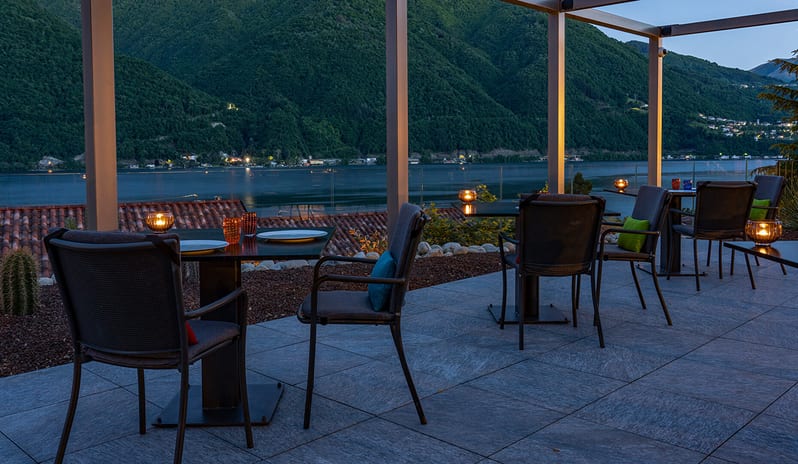 La Musa Restaurant & Rooftop Terrace Candlelit outdoor restaurant terrace overlooking a lake surrounded by mountains at twilight at ARIA Retreat & SPA by Kenwood Travel