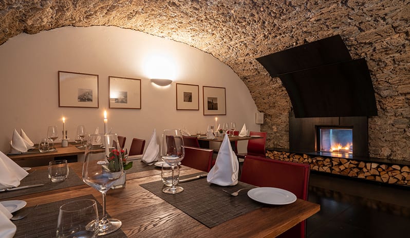 La Masseria Restaurant Warmly lit restaurant interior featuring stone arch ceilings, romantic candlelit tables, red chairs, and a cozy fireplace at ARIA Retreat & SPA by Kenwood Travel