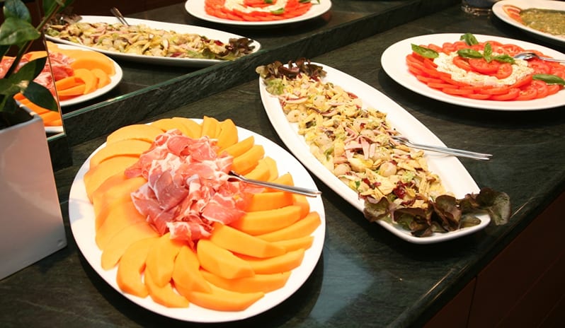 La Veranda & San Marco Restaurant Veranda buffet counter display with prosciutto melon platter, caprese salad, and fresh appetizers at ARIA Retreat & SPA by Kenwood Travel
