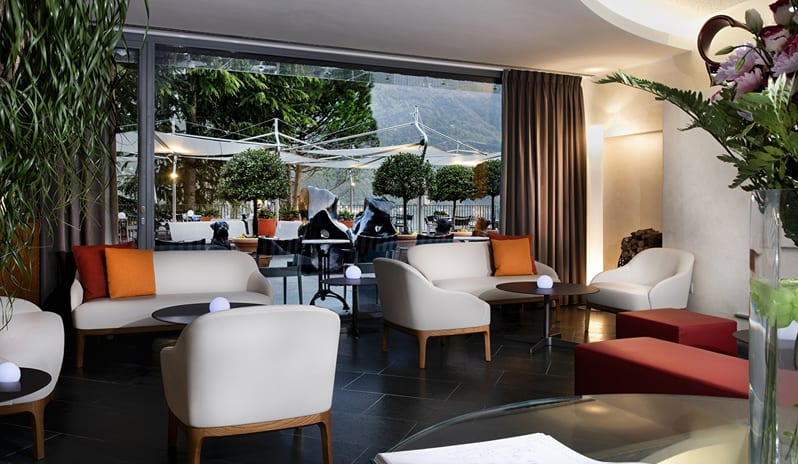 San Marco Lounge & Bar Modern lounge seating area with cream sofas, coffee tables, and floor-to-ceiling windows looking onto a terrace at ARIA Retreat & SPA by Kenwood Travel