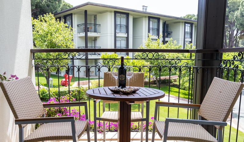Family Suite outdoor terrace with patio seating, an ornate metal railing, and a scenic view of the hotel grounds and landscaping at Gloria Verde by Kenwood Travel