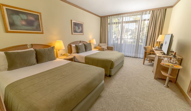 Standard Room two beds with olive green bedding, a work desk, and large windows with sheer curtains at Gloria Verde by Kenwood Travel