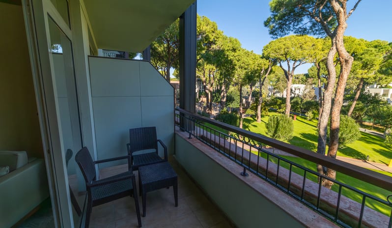 Standard Room overlooking a manicured lawn, walking paths, and tall trees under a clear blue sky at Gloria Verde by Kenwood Travel