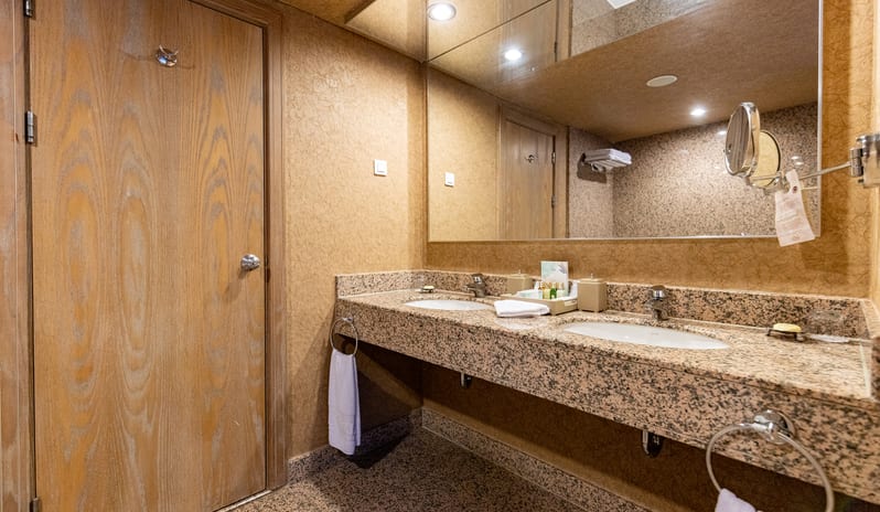 Select Villa granite double vanity counter with two sinks, a large mirror, and warm lighting at Gloria Verde by Kenwood Travel