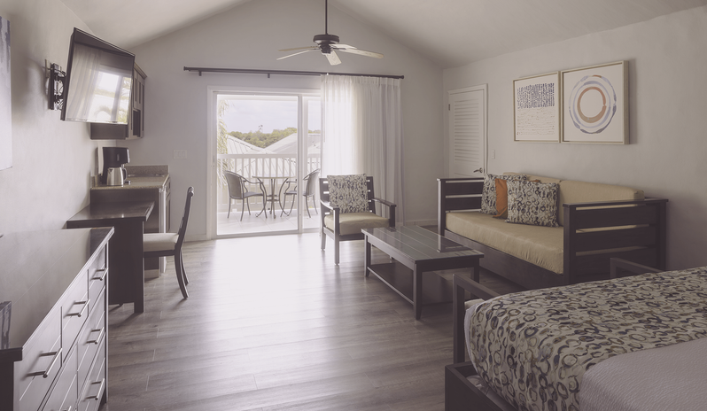 Hillside Suite Garden/Resort Views living area with sofa, desk, and balcony access at The Verandah Antigua by Kenwood Travel