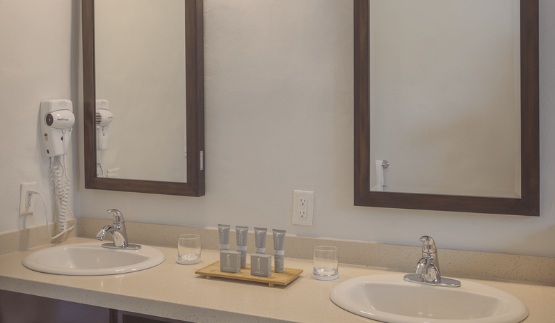 Hillside Suite Garden/Resort Views bathroom vanity featuring double sinks, twin mirrors, and warm lighting at The Verandah Antigua by Kenwood Travel