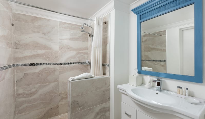 One Bedroom Pool Garden View Suite bathroom featuring a walk-in shower, granite vanity, and large framed mirror at The Club Barbados Resort & Spa by Kenwood Travel