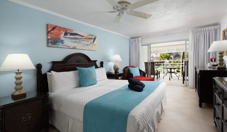 Superior Garden View bedroom with dark wood furnishings and sliding door to a balcony at The Club Barbados Resort & Spa by Kenwood Travel