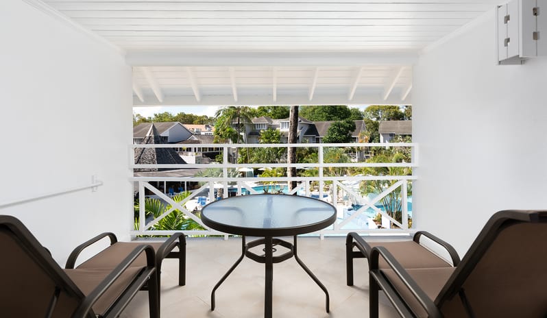 Superior Garden View balcony with lounge chairs and a table looking over the resort pool at The Club Barbados Resort & Spa by Kenwood Travel