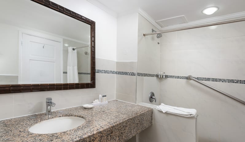 Superior Garden View bathroom with granite vanity top, mirror, and tiled shower area at The Club Barbados Resort & Spa by Kenwood Travel