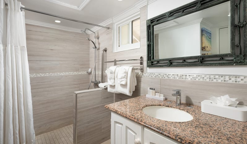 Ocean Loft Ocean View Hotel bathroom featuring a walk-in shower, granite vanity, and large framed mirror at The Club Barbados Resort & Spa by Kenwood Travel