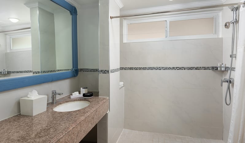 Superior Garden View bathroom with granite vanity top, blue mirror frame, and tiled shower area at The Club Barbados Resort & Spa by Kenwood Travel