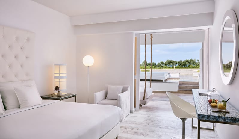 Swim-up Guestroom Sea View Modern white resort bedroom suite opening onto a private outdoor patio at Grecotel LUXME White by Kenwood Travel