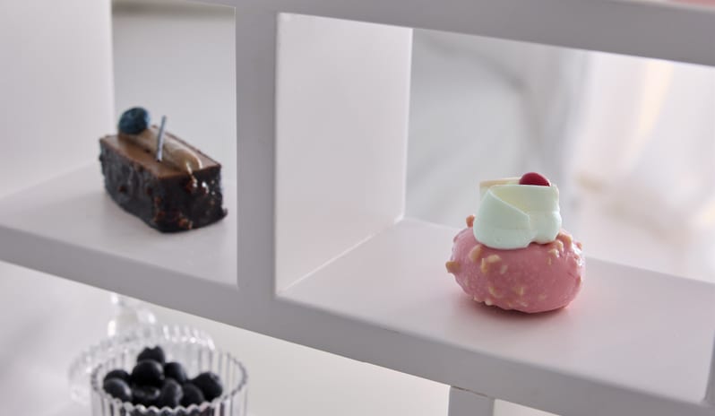 Prestige Guestroom Sea View Miniature gourmet pastries and fresh berries on a white modern tier stand at Grecotel LUXME White by Kenwood Travel