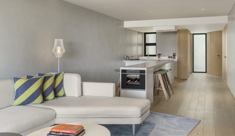 Superior Room Modern luxury suite with open-concept sectional sofa lounge area, island bar with stools, and built-in wine fridge at W Algarve by Kenwood Travel