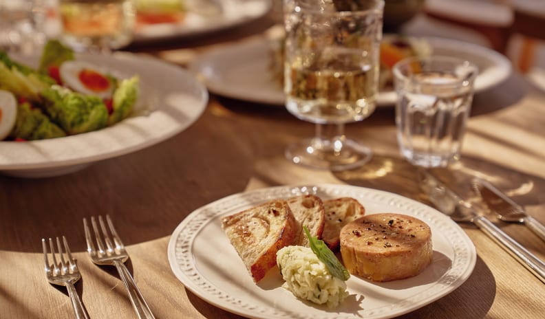 La Plage Luxury Mediterranean style resort outdoor gourmet lunch featuring pate with toasted bread, fresh salad, and white wine in warm sunlight at Ikos Kissamos by Kenwood Travel