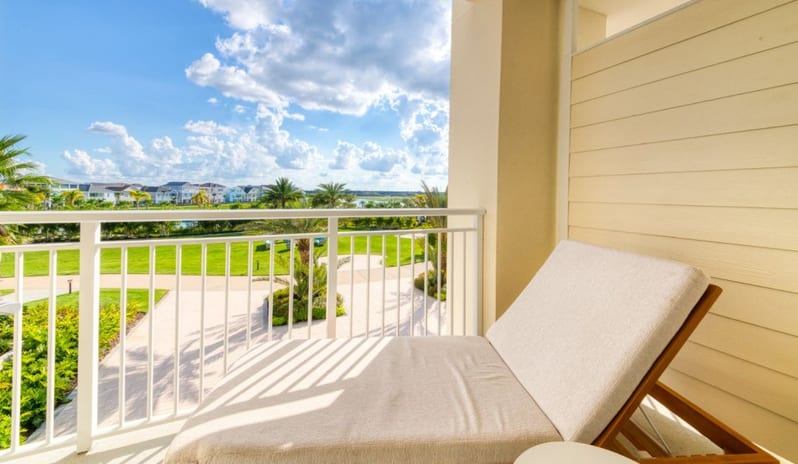 One Bedroom Suite Comfortable lounge chair on a hotel balcony facing a bright tropical garden courtyard at Margaritaville Resort Orlando by Kenwood Travel
