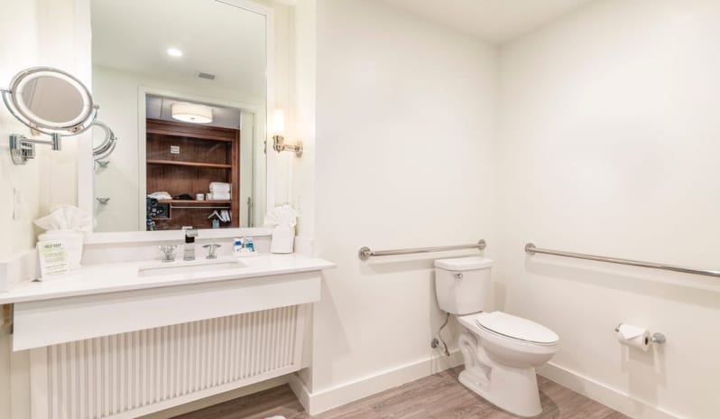 One Bedroom Suite Wheelchair-accessible resort suite bathroom equipped with safety rails, vanity mirror, and toilet at Margaritaville Resort Orlando by Kenwood Travel