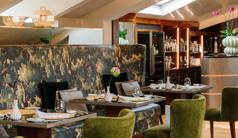 Altariva Restaurant Dining tables with green velvet chairs and botanical tapestry bench next to the bar at Palazzo Venezia by Kenwood Travel