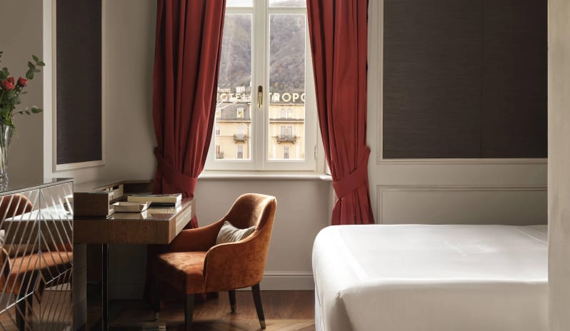 Standard Room Elegantly designed luxury hotel bedroom with a wooden writing desk, velvet armchair, red drapes, and a city view at Palazzo Venezia by Kenwood Travel