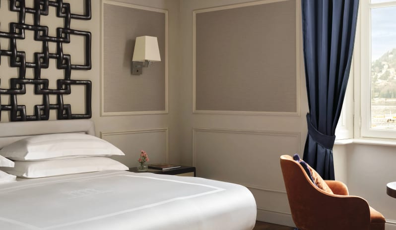 Suite King bed with white crisp linens, black fretwork wall detail, and lake view window at Palazzo Venezia by Kenwood Travel