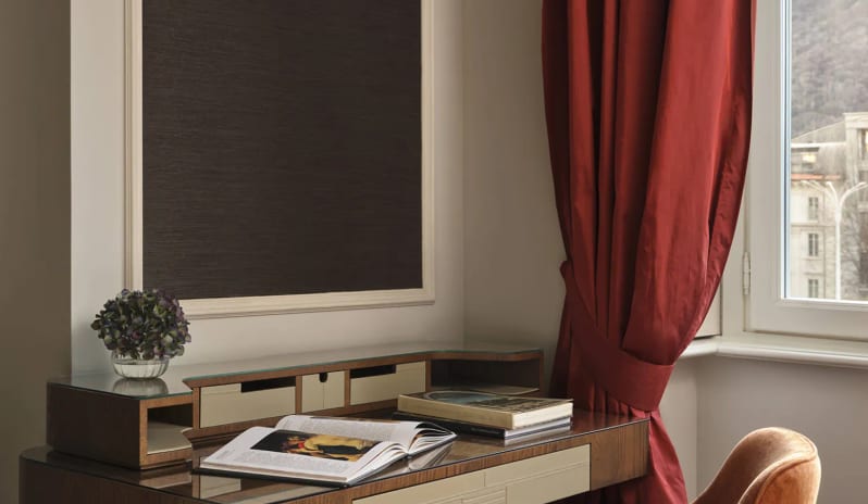 Standard Room writing desk and velvet chair positioned next to a window with red drapes at Palazzo Venezia by Kenwood Travel