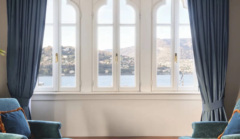 Corner Junior Suite Teal armchairs and large arched windows with a lake view at Palazzo Venezia by Kenwood Travel