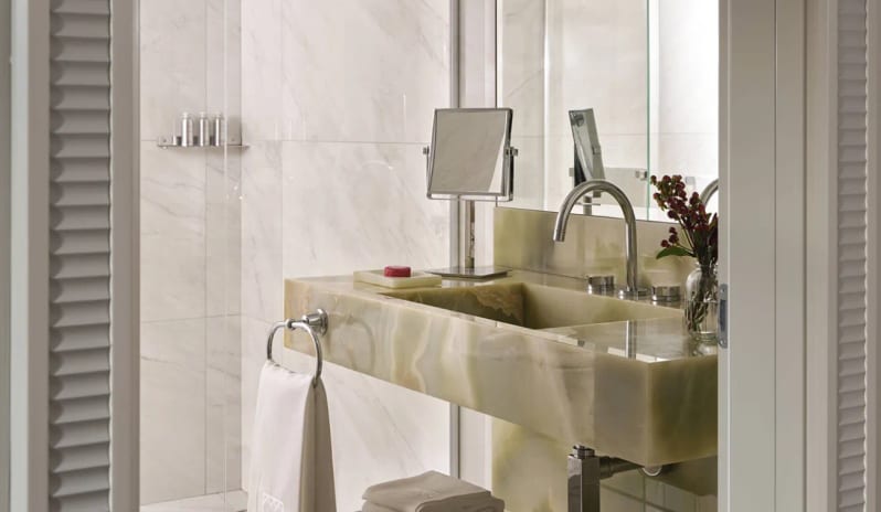 Standard Room Bright marble bathroom with custom stone vanity and walk-in glass shower at Palazzo Venezia by Kenwood Travel
