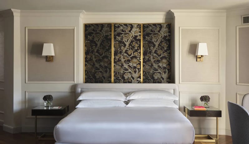 Corner Junior Suite King bed with crisp white linens and a dark floral accent wall panel in a suite at Palazzo Venezia by Kenwood Travel