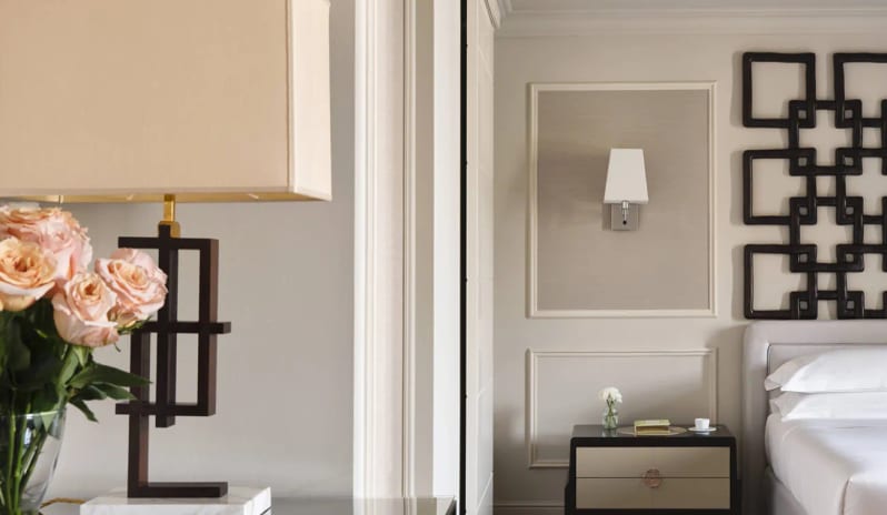 Suite Bedroom entryway with table lamp, flower vase, and king bed setup at Palazzo Venezia by Kenwood Travel