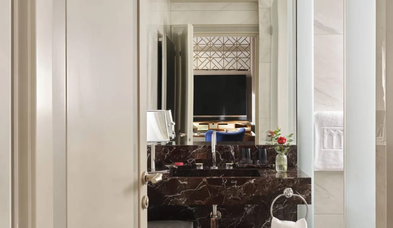 Deluxe Double Room Dark marble vanity counter and mirror reflection in a luxury suite bathroom at Palazzo Venezia by Kenwood Travel