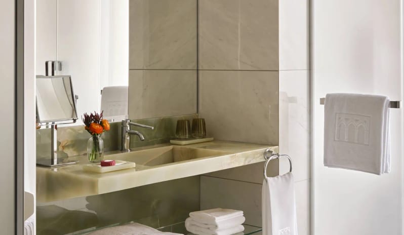 Premium Room Green onyx stone vanity and glass shelf with white towels in a luxury suite bathroom at Palazzo Venezia by Kenwood Travel