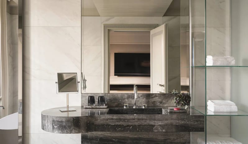 Suite Dark marble vanity counter with mirror and glass towel shelving in a suite bathroom at Palazzo Venezia by Kenwood Travel