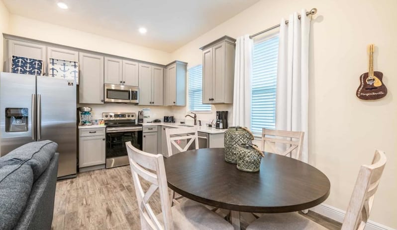Two Bedroom Villa Fully equipped kitchen with grey cabinets next to a round dining table and four chairs at Margaritaville Resort Orlando by Kenwood Travel