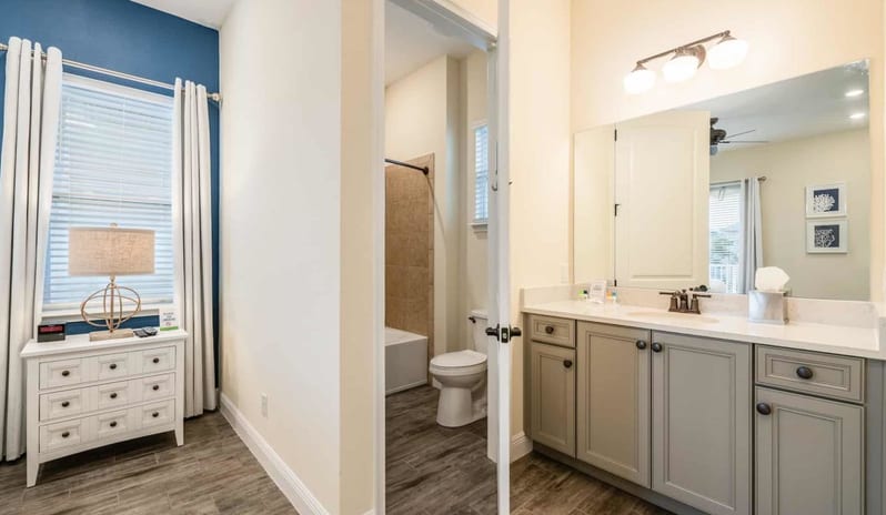 Two Bedroom Villa Spacious bathroom vanity next to a doorway looking into an adjacent bedroom at Margaritaville Resort Orlando by Kenwood Travel