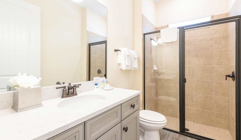 Two Bedroom Villa Bathroom interior with grey vanity, large mirror, toilet, and tiled walk-in shower at Margaritaville Resort Orlando by Kenwood Travel