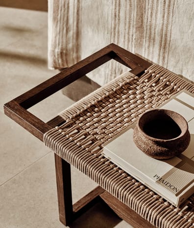 Deluxe Three Bedroom Suite Private Garden Pool View Dark wood and woven rope bench with minimalist decor accessories at Ikos Kissamos by Kenwood Travel