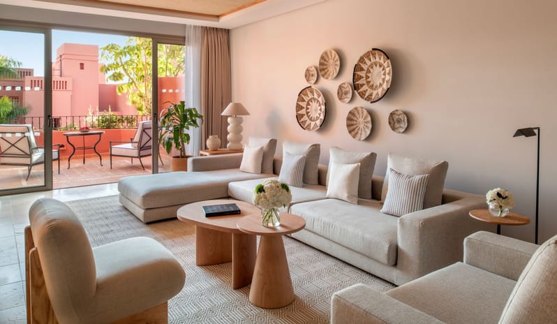 Citadel Two Bedroom Family Resort View Modern interior decor of a hotel suite living area showcasing natural beige tones, woven basket wall decorations, and a view of a terrace with terra-cotta architecture at Ritz Carlton Tenerife Abama by Kenwood Travel