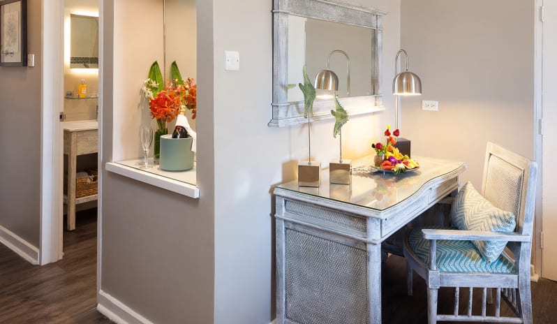 Classic Garden View Coastal resort room writing desk featuring a cushioned chair with blue patterned fabric, decorative starfish statues, and a champagne welcoming setup in an adjacent alcove at Sea Breeze Beach House by Kenwood Travel