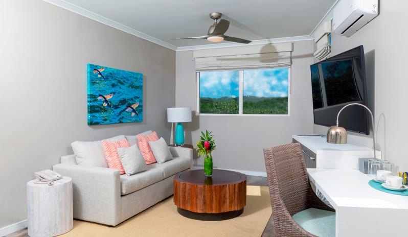 Luxury Suite four Bedroom Ocean Front Coastal hotel lounge area displaying vibrant blue koi fish canvas artwork, a turquoise bedside lamp, split air conditioning unit, and a window with garden views at Sea Breeze Beach House by Kenwood Travel