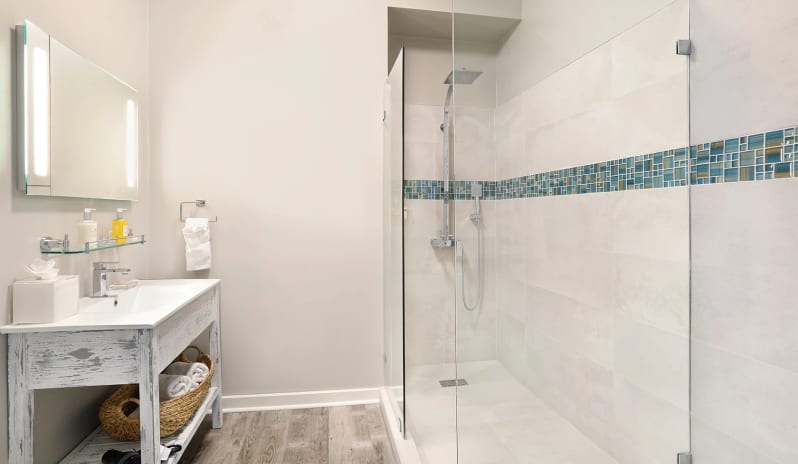 Classic Suite Two Bedroom Coastal resort en-suite bathroom with a spacious walk-in shower, rainfall showerhead, whitewashed vanity table, and neutral beige wall finishes at Sea Breeze Beach House by Kenwood Travel