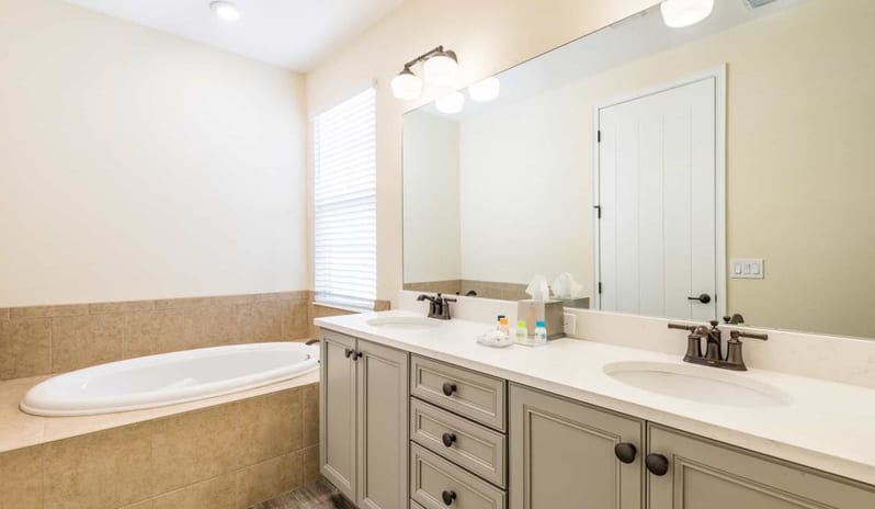 Three Bedroom Villa Bathroom with grey double vanity, wide mirror, and built-in soaking tub at Margaritaville Resort Orlando by Kenwood Travel
