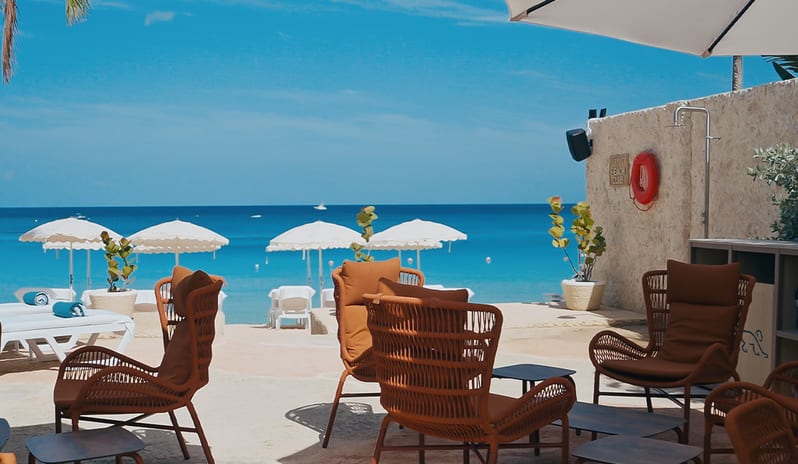 The Beach Club Beachfront lounge area at a tropical luxury resort on a clear day at Blue Monkey Hotel Beach Club by Kenwood Travel
