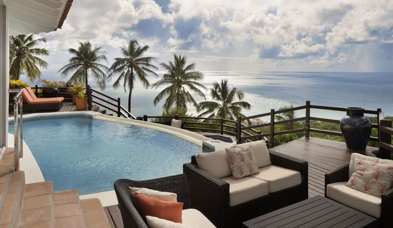 Dukes Manor Luxury beach resort terrace with infinity pool, outdoor lounge furniture, sunbed, and panoramic ocean views framed by tropical palm trees at Windjammers Landing by Kenwood travel