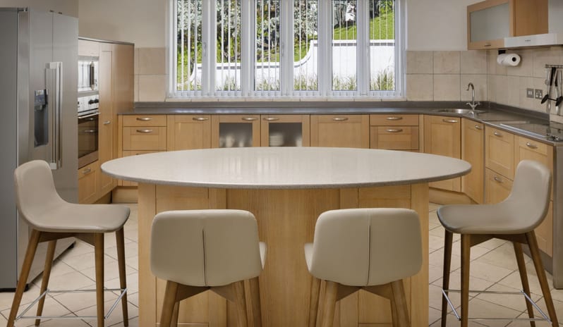 Royal Manor Spacious Fully equipped luxury resort kitchen featuring a oval island counter, modern high bar chairs, and ample wooden storage cabinets at Windjammers Landing by Kenwood travel